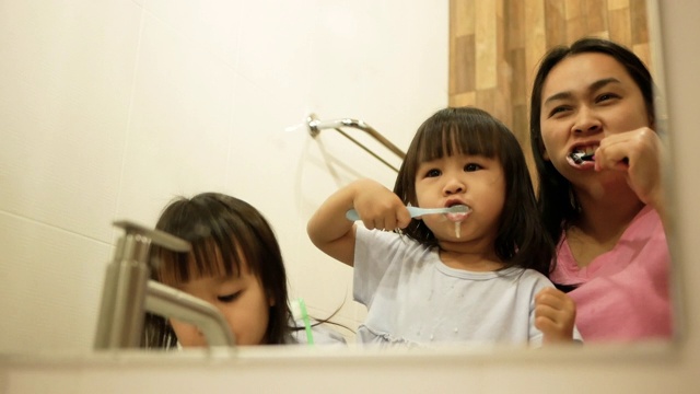 快乐的母女俩在浴室里一起刷牙。口腔卫生的概念。视频素材