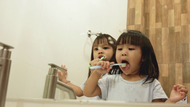快乐的姐妹小女孩在浴室里一起刷牙。口腔卫生的概念。视频下载