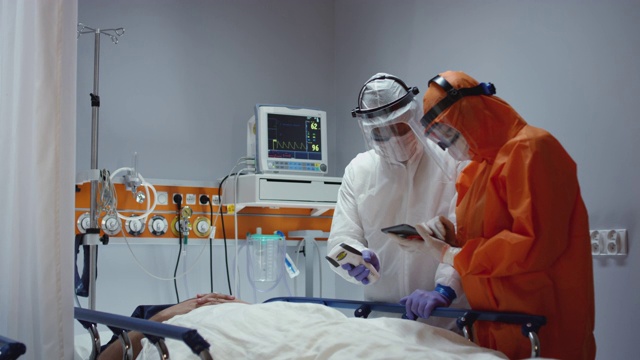 慢镜头:护士测量冠状病毒患者的体温，并咨询领先医生-宽摄影。拍摄于5K R3D视频素材