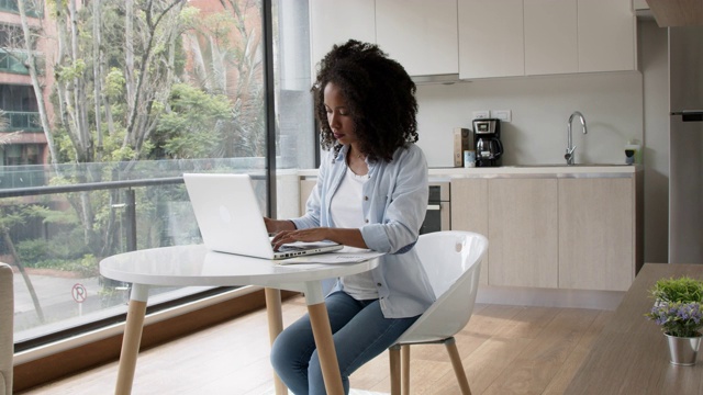 一个漂亮的黑人女人在家里处理文件和笔记本电脑视频素材