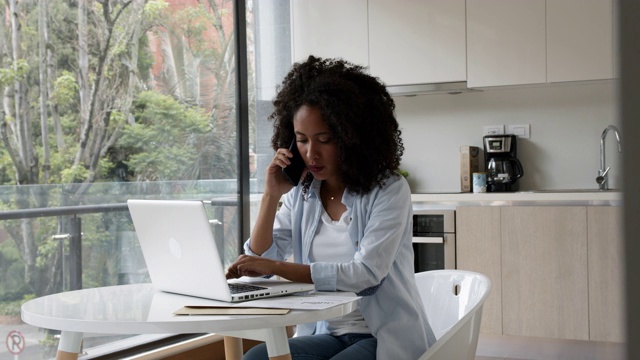 年轻的非洲裔美国妇女在家工作，一边打电话一边在电脑上打字视频下载