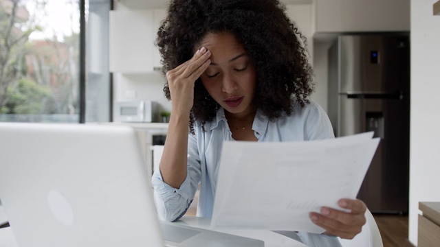 压力很大的黑人妇女在家工作，看着一份文件非常沮丧视频下载