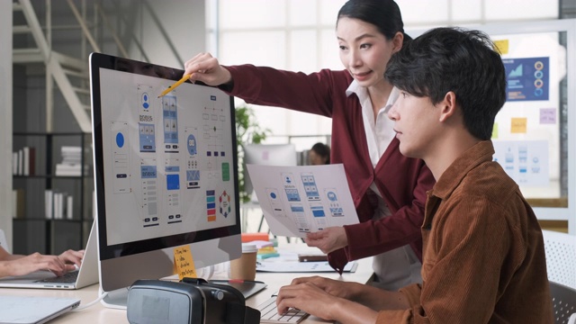 亚洲女性领导者反馈手机应用设计线框原型与开发者在桌面电脑在现代办公室视频下载
