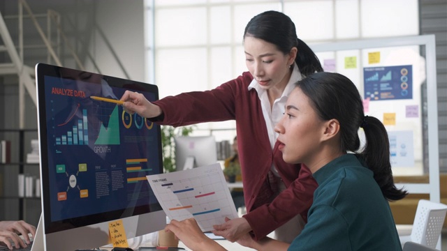 亚洲女性领导人讨论在时间表上的最后期限为移动应用程序设计线框原型与设计师在桌面电脑在现代办公室视频下载