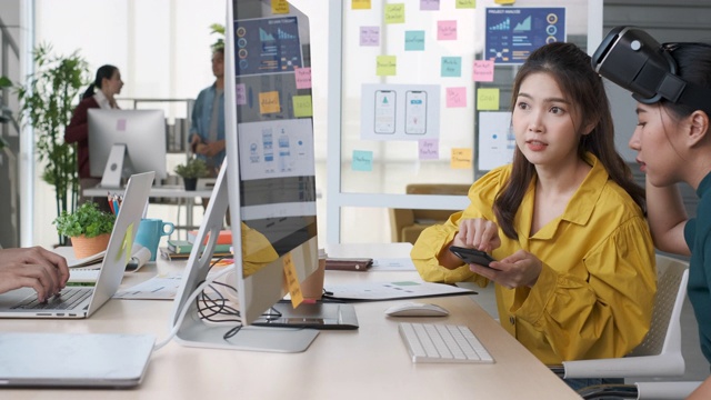 年轻的亚洲设计师团队戴着vr眼镜(虚拟现实)测试移动应用ux,ui从桌面电脑开发软件在现代创意办公室视频下载