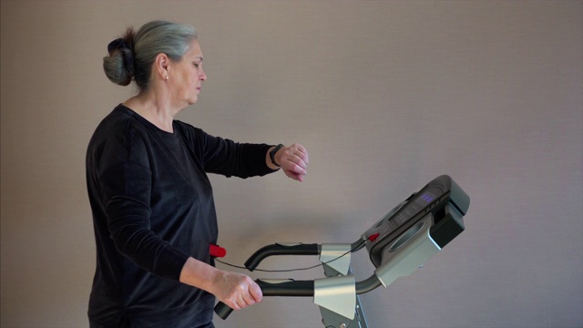 白人妇女在跑步机上锻炼。她正在改变训练模式速度。视频下载