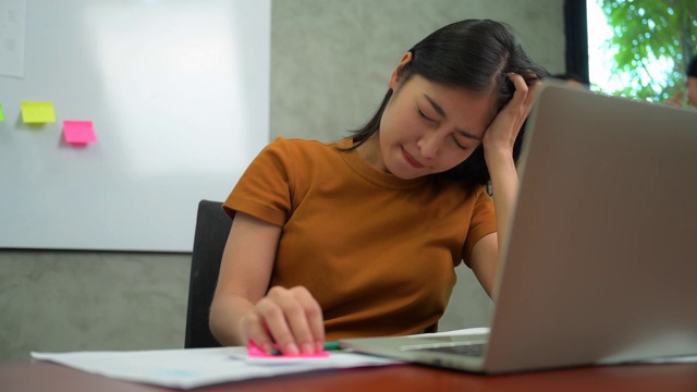 疲惫和无聊的年轻亚洲商务办公室女性工作在一个办公室的电脑视频素材