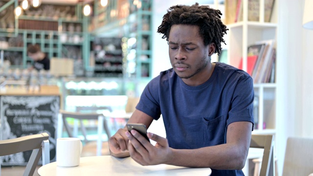 非洲男子在咖啡馆用智能手机应对损失视频素材