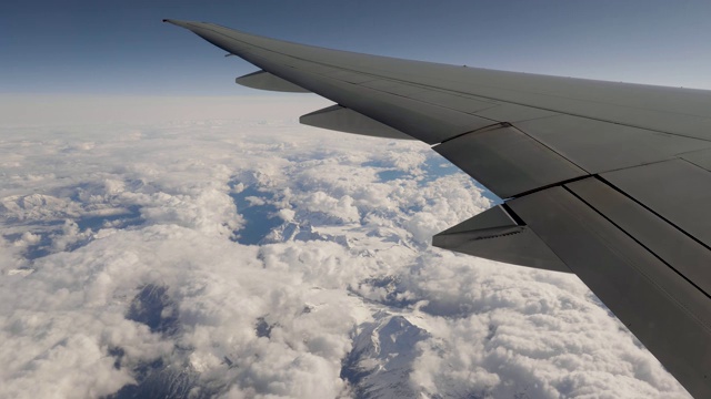 从窗口看飞机在机翼和山脉在雪和云视频下载