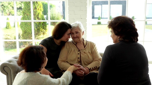 一位白发苍苍的老妇人坐在她女儿和孙女的旁边视频素材