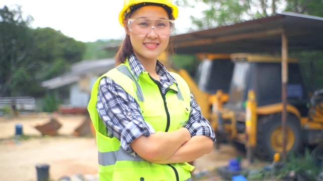 亚洲女工程师站在挖掘机的长柄勺旁，检查一个方案视频素材