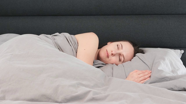 独自睡在床上的女人。孤立的年轻女性睡在空荡荡的客厅里。生活方式的概念视频素材