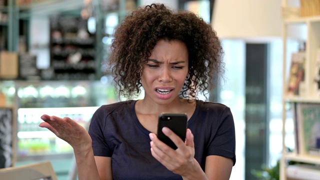 年轻的非洲女性在智能手机上的失落画像视频素材