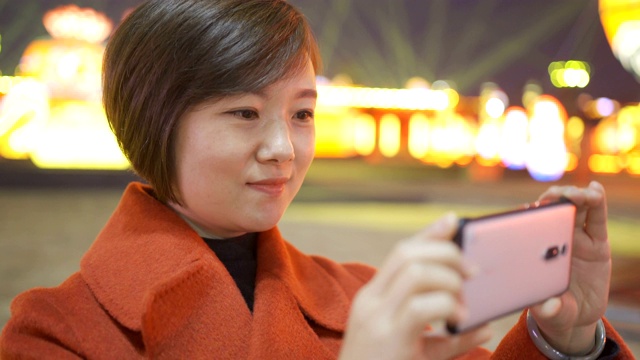 中国春节期间，一名女子用智能手机拍摄城市景观视频素材