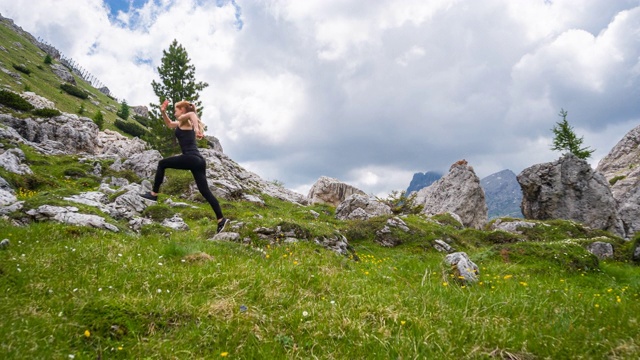 快乐的女运动员在山腰的绿色草地上奔跑视频素材