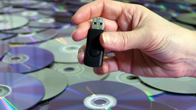 女人的USB记忆棒旁边的CD和DVD光盘。新老技术理念视频下载