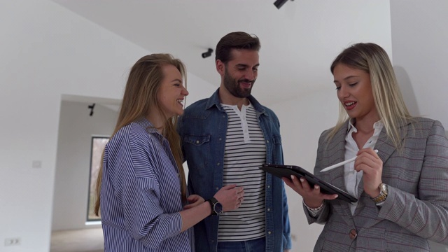 房地产经纪人向一对年轻夫妇展示明亮的新公寓视频素材