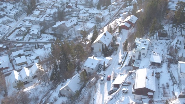 无人机拍摄到一辆红色汽车在雪地里穿过居民区视频下载