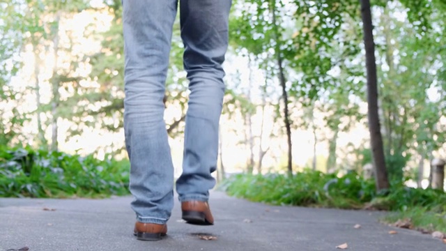 一个男性鞋走在街道上的特写，公园在慢动作。视频下载
