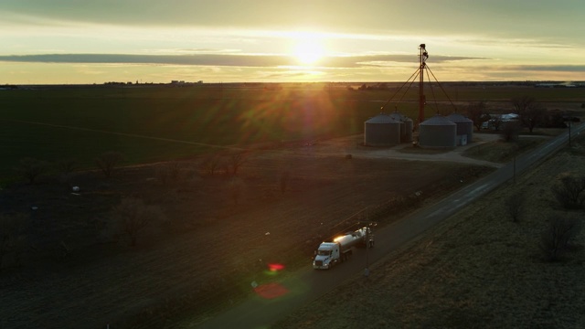 无人机拍摄牛奶罐车驶离奶牛场经过筒仓视频下载