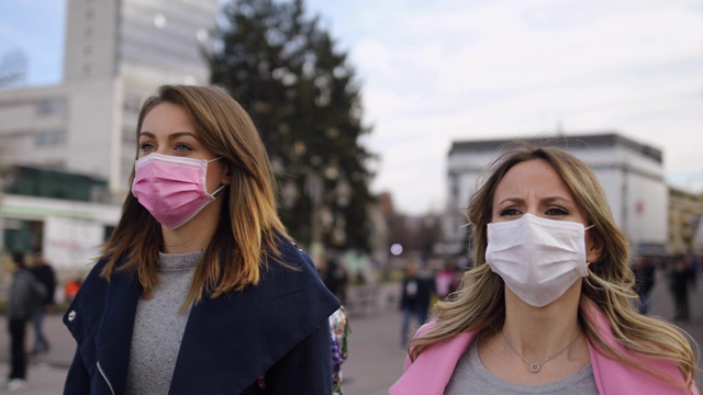 保护。两个戴着防污染口罩的年轻女子走在街上视频素材