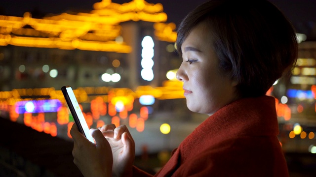 中国春节期间，一名女子用智能手机拍摄城市景观视频素材