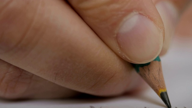 艺术家手绘木笔在纸上书写。一个男人在纸上写东西的特写超级微距镜头。特写镜头。UHD 4 k。视频素材