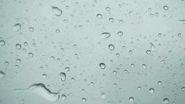 雨点落在窗外的玻璃上。关闭了。缓慢的运动。雨落在玻璃上。雨滴落在车窗背景上。秋天天气不好。视频素材