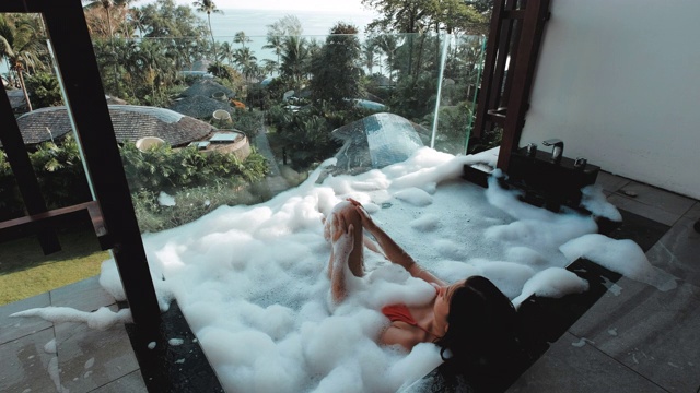 亚洲女人放松在户外浴池与热带海洋豪华水疗酒店，生活理念视频下载