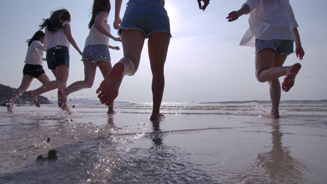 慢镜头:日落时分，一群女人在海滩上跑步视频素材