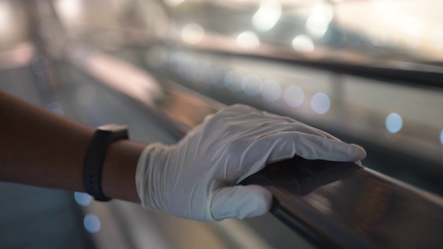 在公共场所应对新冠肺炎疫情时，手持塑料手套的人手握电梯拉手视频素材