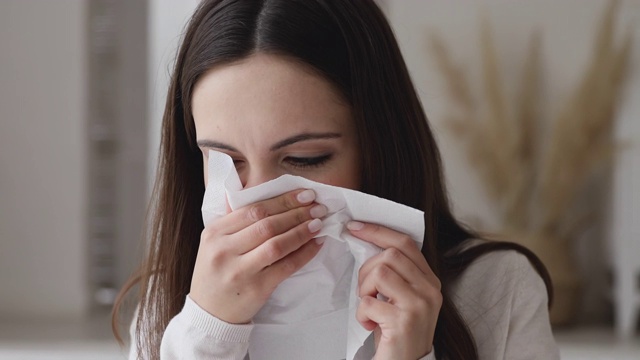 生病过敏的年轻女子打喷嚏在纸巾擤鼻涕视频素材