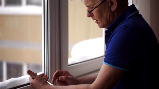 戴眼镜的老人使用手机。穿着蓝色马球衫的成熟老人。视频素材