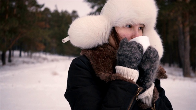 可爱的女孩的近距离与咖啡在她的手在冬天的森林视频下载