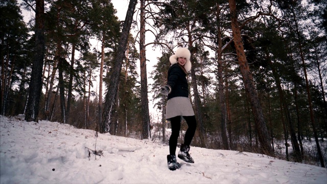 年轻的女模特走在冬天的森林里，在树林里的雪地里。视频下载
