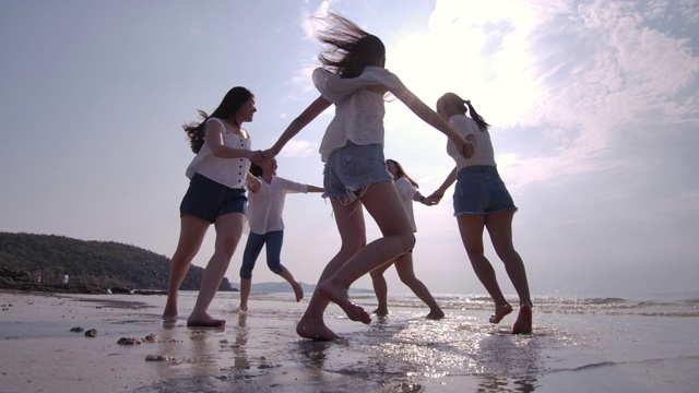 SLO MO女子朋友群在日落海滩玩。海滩度假旅游概念视频素材