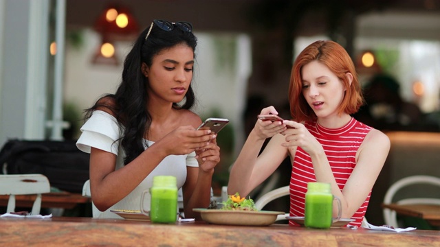 来自不同文化的女孩用手机拍照。女性朋友坐在餐厅视频素材