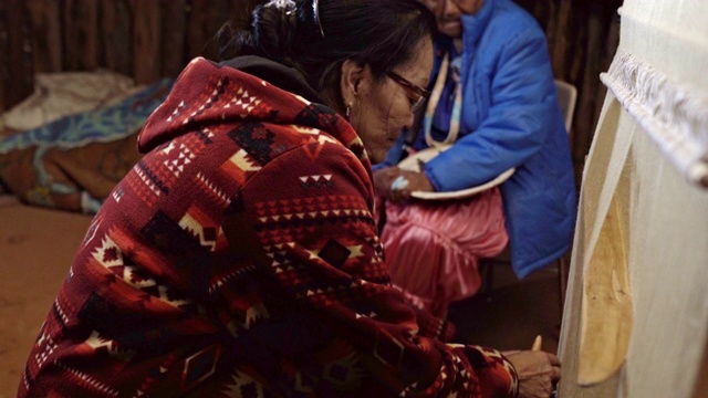 一位纳瓦霍妇女在织布机上编织马鞍毯，背景是她的母亲视频素材