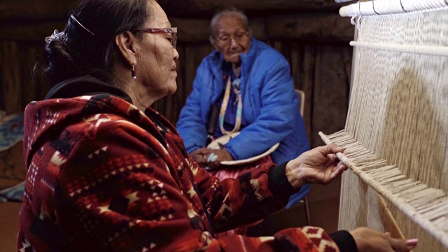 一位纳瓦霍妇女在织布机上编织马鞍毯，背景是她的母亲视频素材