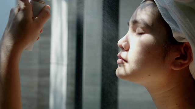 亚洲妇女用矿泉水喷雾进行面部护理。视频素材