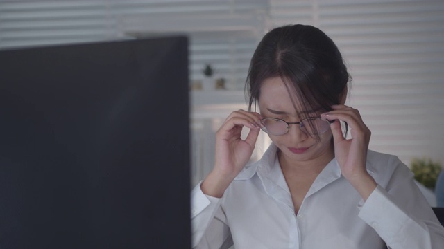 美丽疲惫的亚洲女员工在公司办公室的台式电脑上工作视频素材