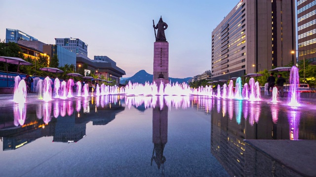 游客在韩国首尔市光华门广场参观彩色地板喷泉和海军上将李舜臣雕像视频下载