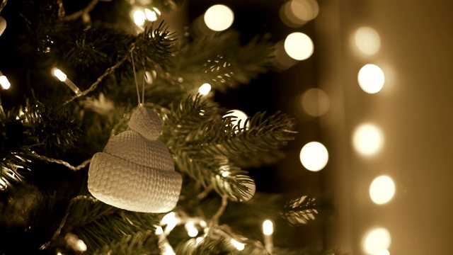 女人双手将圣诞装饰品挂在圣诞树上，挂着圣诞彩灯视频下载