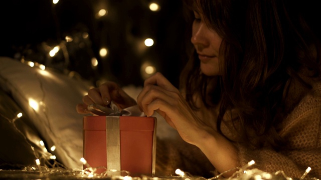 女孩许愿并打开了一个圣诞礼物包。圣诞节和新年的概念。女孩很高兴，笑了。视频下载
