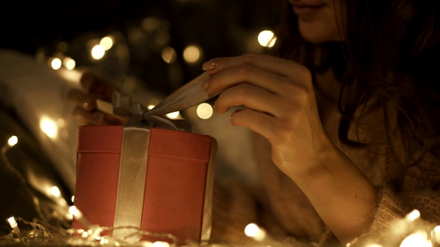 弯头美女打开圣诞礼盒。以散景为背景灯光营造节日气氛视频下载