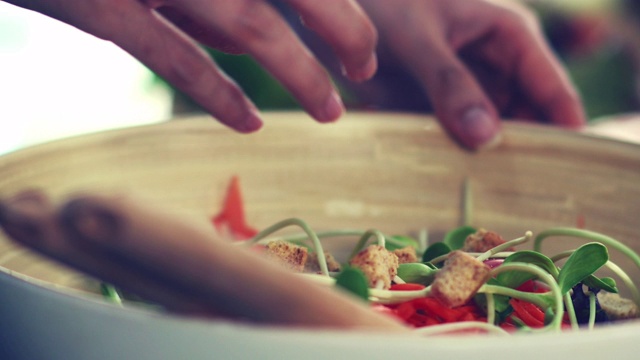 女人用手把蔬菜拌在沙拉碗里。视频素材