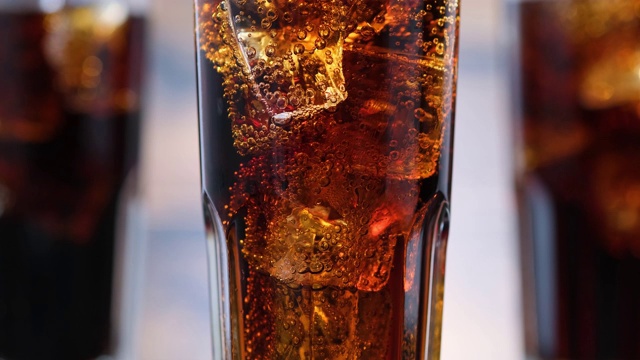 特写气泡在玻璃与可乐和冰块。气泡饮料冒了出来视频素材