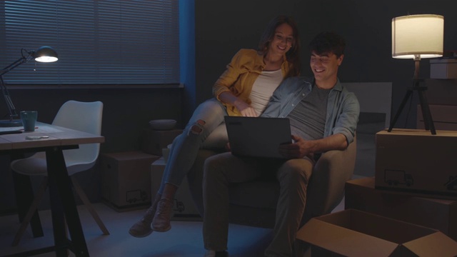 一对夫妇在他们的新家连接一个笔记本电脑视频素材