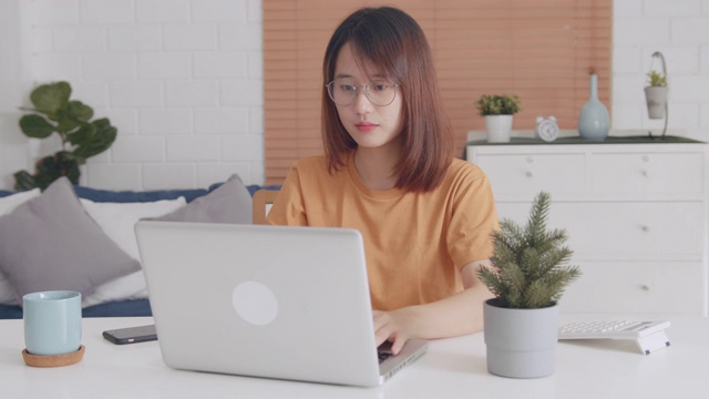 有魅力的亚洲女人看着电脑笔记本屏幕上的键盘打字聊天，浏览互联网视频素材
