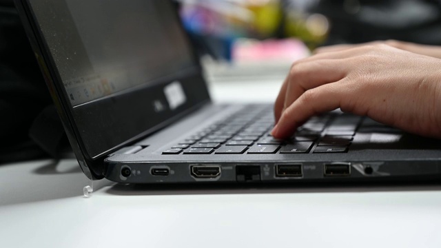 在办公室里用笔记本电脑打字的4K女人。近距离女人的手写在笔记本电脑键盘上。近距离敲击键盘，写电子邮件或在电脑上工作。视频素材